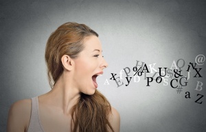Side view portrait woman talking with alphabet letters coming out of her open mouth isolated grey wall background. Human face expressions, emotions. Communication, information, intelligence concept